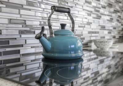 Image: blue kettle on induction hob against grey patterned wall ethical environmentally friendly
