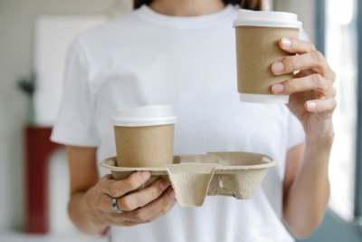 Woman holding two takeaway cups of hot drinks