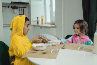 Two children eating breakfast cereal at table