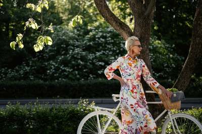 Older woman in patterned dress and white bicycle outdoors