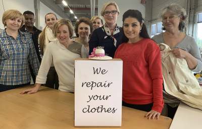 Group of people holding sign which reads 'we repair your clothes'
