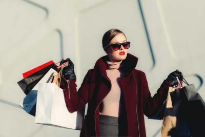 Woman wearing coat and carrying lots of fashion shopping bags