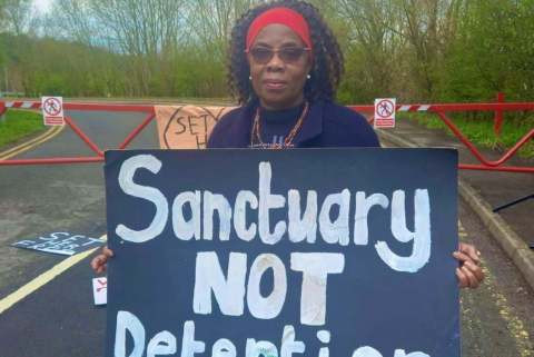 Image of woman holding sign saying "Sanctuary not detention"