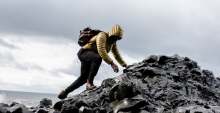 Hiker in jacket climbing over rocks