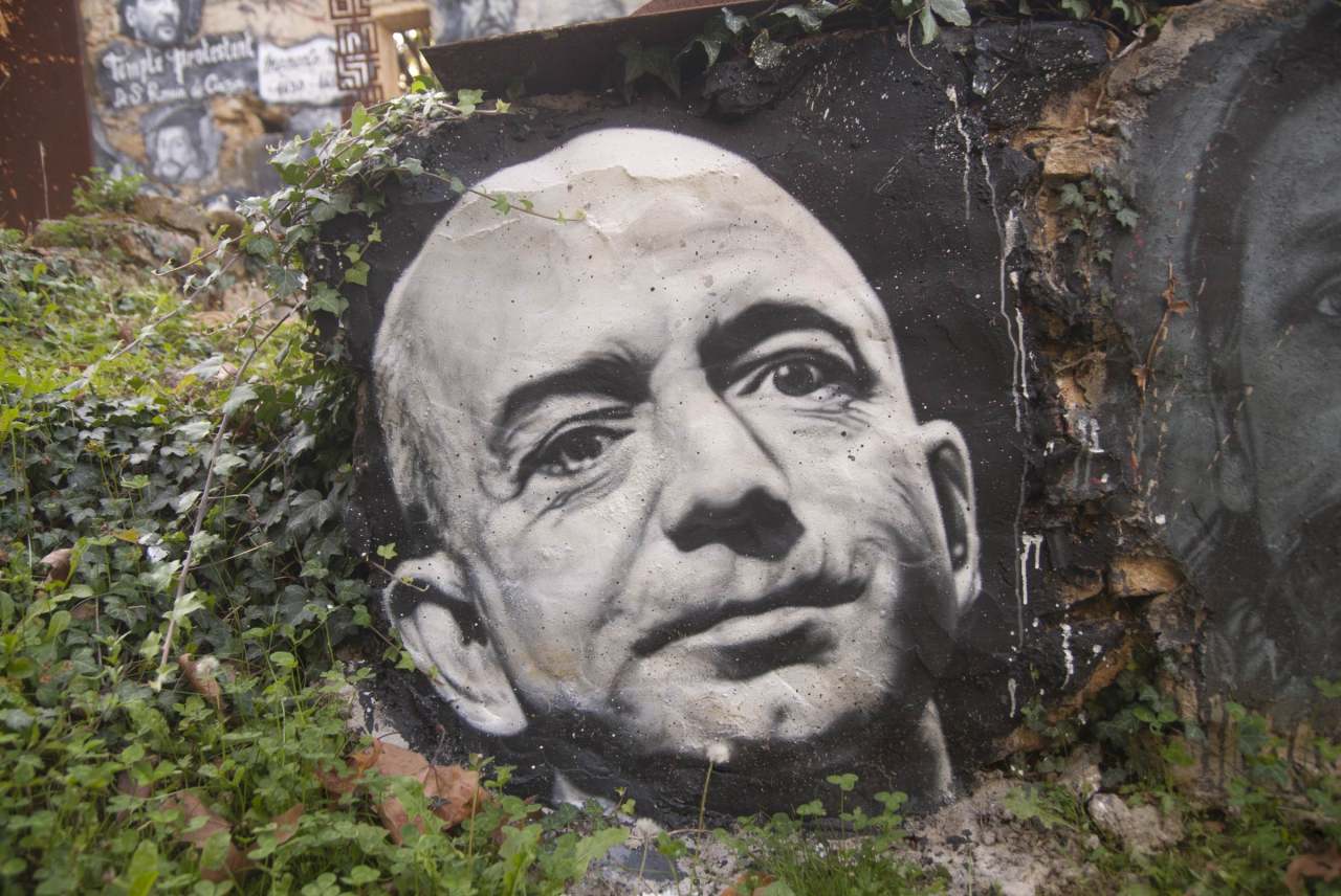 image: black and white graffiti portrait of jeff bezos surrounded by leaves