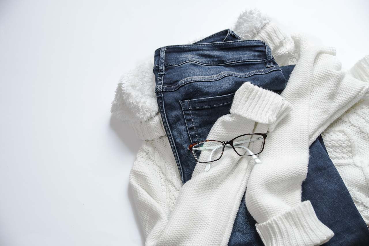 Wite jumper, blue jeans and glasses in a pile on floor