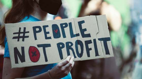 Woman holding banner which reads 'people not profit'
