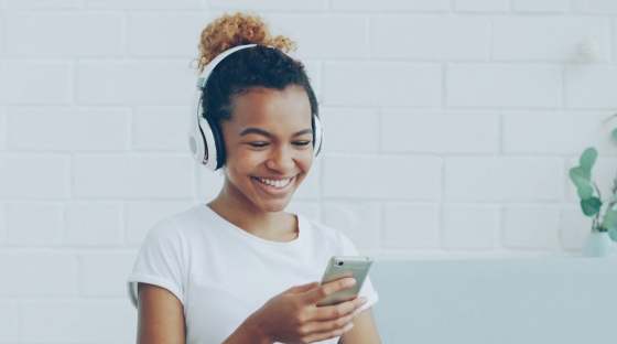 Woman with headphones on sitting on a sofa, listening to streamed music