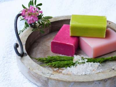 Three bars of soap in a wooden dish with flowers and herbs