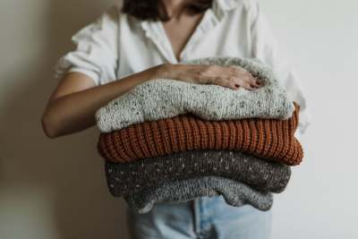 Woman holding pile of jumpers