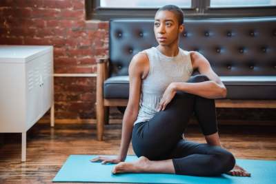 Woman sitting in yoga pose on mat in living room