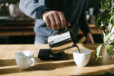 Person pouring coffee into coffee cup