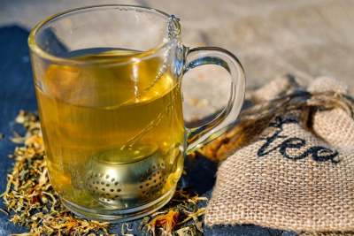 Clear glass mug with golden coloured tea with infuser in the mug