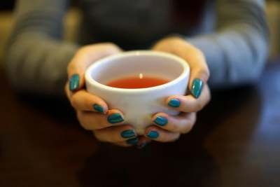 Hands holding white cup of tea
