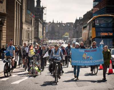 Group of cyclists with banner which reads 'this machine fights climate change'