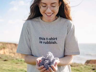 Woman wearing t-shirt which says 'this t-shirt is rubbish' and she is holding recycled fibres in hands