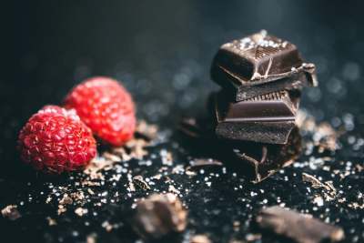 Small squares of dark chocolate and two raspberries