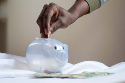 Person putting coins into piggy bank