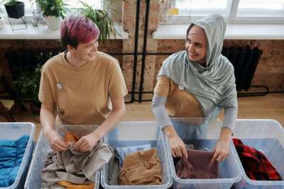 Two women sorting clothes in boxes