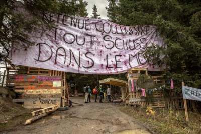 Protest camp in woods with sign in French