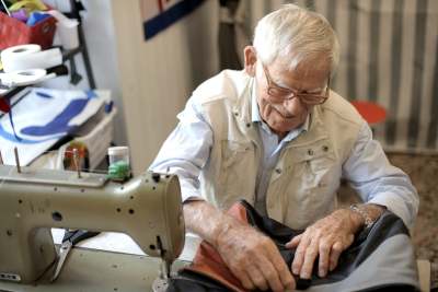 Elderly man using sewing machine to repair clothes