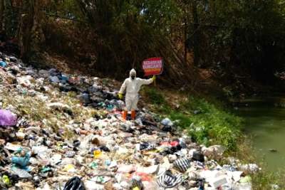 Man holding sign standing in litter dump