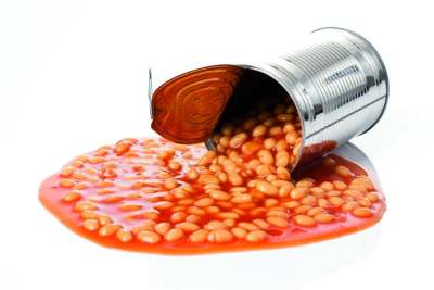 Open tin of baked beans lying on side with beans spilt out