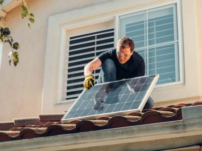 Man fixing solar panel to roof
