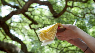Person holding notepad with trees behind