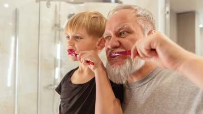 Older man and young boy brushing teeth