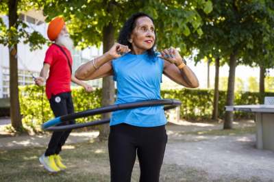 Man in turban and older woman exercising outdoors in park