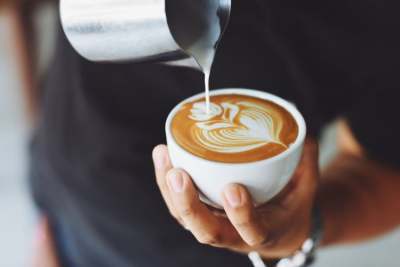 Person pouring milk into coffee cup