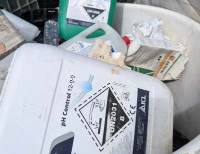 Rubbish bin full of plastic cartons of chemicals