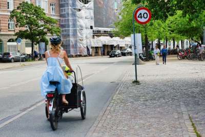 Woman cycling in segregated cycle lane with front-loaded cargo bike / trike