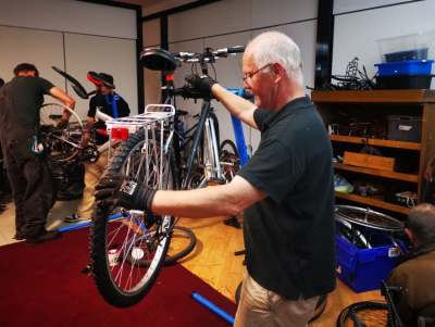 Older man checking a bike in a bike workshop