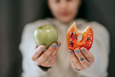Person holding an apple and a donut