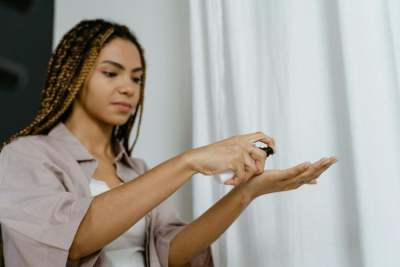 Darker skin female putting lotion on hands