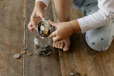 Child tipping coins into a glass jar