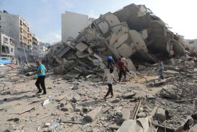 Destroyed buildings in ruins, with people searching through rubble, Gaza
