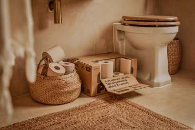 Unbleached toilet rolls in basket and box next to toilet