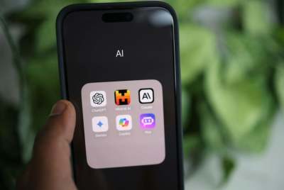 Person holding a mobile phone with symbols of AI tools on the screen
