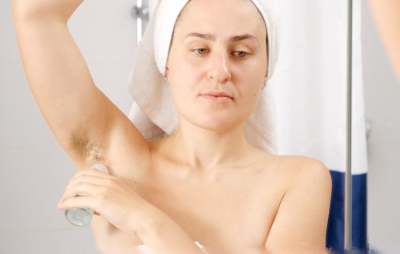 Person applying deodorant to unshaved armpit
