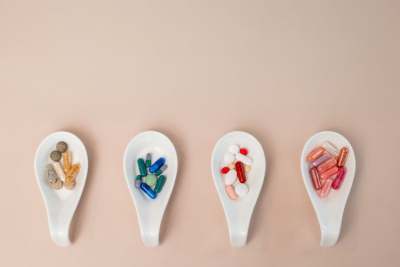 Four Chinese soup spoos filled with different coloured pills and supplements