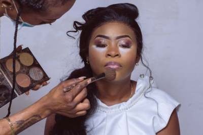 Person applying makeup to Black woman 