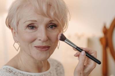 Senior woman applying makeup to face