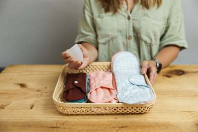 Women holding basket of reusable cloth menstrual pads and menstrual cup