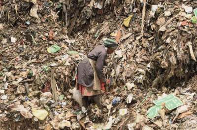 Woman picking through large pile of waste