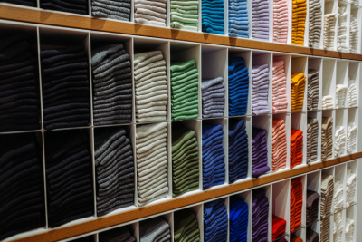 Shelves of coloured clothing folded, probably jumpers