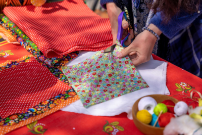 Person cutting up fabric on table with lots of colourful cloths