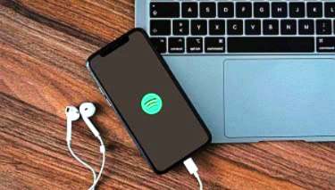 Spotify logo on mobile phone resting on laptop keyboard